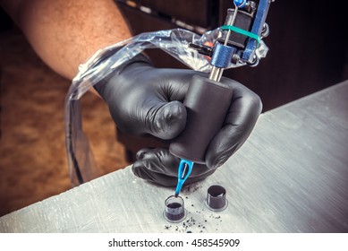 Tatoo Artist Working With A Tatoo Machine With Black Gloves On And Use A Black Inks For Tatooing At The Tatoo Salon Closeup/particulars Of  Tattoo Profession/ Professional Tools For Tatooing