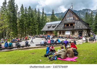 TATRA MOUNTAINS, POLAND - AUGUST 15, 2016: Relaxing Tourist Next To Mountain House. People Resting During Tour In Koscieliska Valley, Hala Ornak. Tatra National Park In Poland.