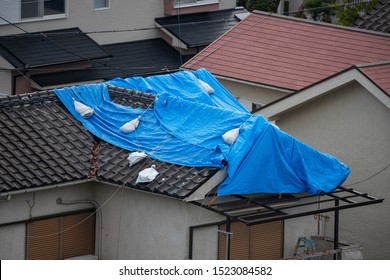 Tattered Blue Tarp On Roof After Strong Typhoon Wind Damage