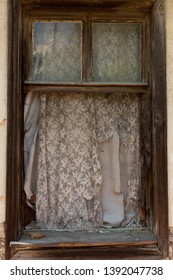 Tattered Curtain At A Glass-less Window In An Abandoned House