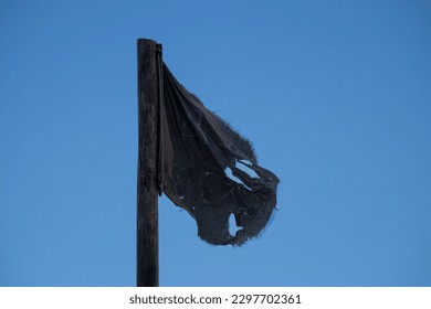 Tattered pirate black flag on sky