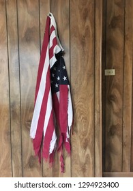 A Tattered And Worn American Flag Hangs On A Wood Panel Wall In An Old Church Basement. 