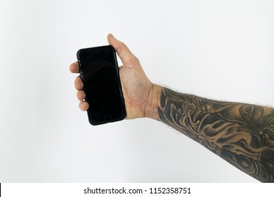 Tattoed arm and hand holding a mobile phone