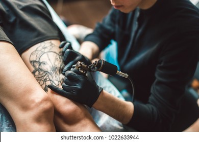 Tattoo Artist In Black Gloves Making A Tattoo On The Foot Girls. Sterile.