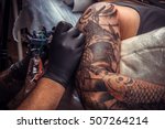 Tattoo artist doing tattoo in tatoo salon./Master makes tattoo in tattoo studio.
