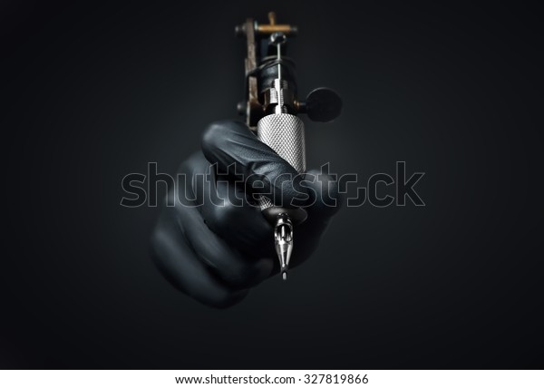Tattoo artist holding tattoo machine on\
dark background, Machine for a tattoo\
concept