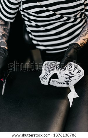 tattoo artist at work. tattooed guy makes a tattoo to a female client. close up of tattoo work. 