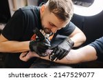 Tattoo master is tattooing a man