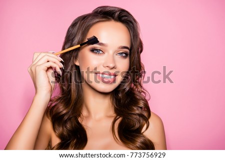 Tattoo, microblading, modeling brows, perfection concept. Attractive gorgeous charming lady with ideal face, healthy shiny clear skin, amazing hairstyle, holds brush in hand, paint her eyebrows