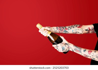 Tattooed arms of a person opening a champagne bottle. The champagne bottle is being opened by tattooed arms against a red background. Tattooed arms with champagne bottle - Powered by Shutterstock