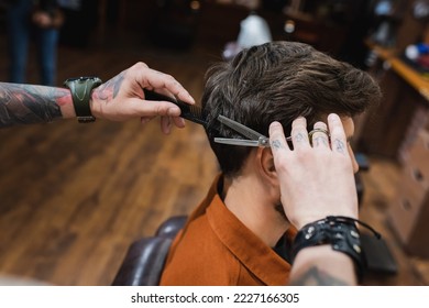 tattooed barber cutting hair of brunette man with thinning scissors - Powered by Shutterstock