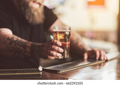 Tattooed bartender with beard working in pub
