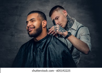 Tattooed Caucasian male barber cutting the beard to Black stylish man. - Powered by Shutterstock