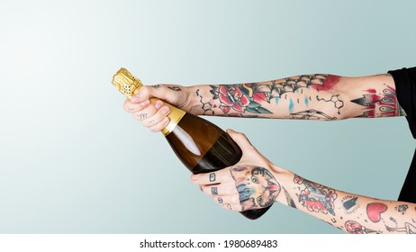 Tattooed hand holding a bottle of champagne - Powered by Shutterstock