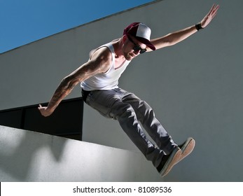 Tattooed Male Parkour Free Runner Jumping Off A Building