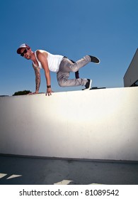 Tattooed Male Parkour Free Runner Climbing Over A Wall