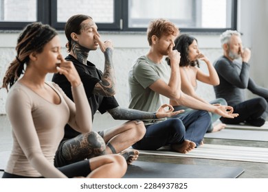 Tattooed man practicing nostril breathing and gyan mudra in yoga class - Powered by Shutterstock