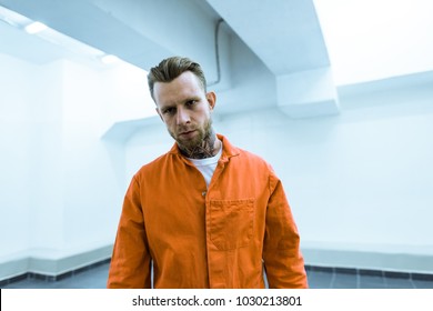 Tattooed Prisoner In Orange Uniform Looking At Camera