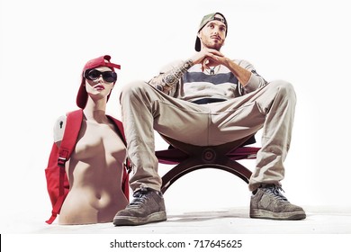 tattooed rap singer posing in studio with a female dummy on a white background