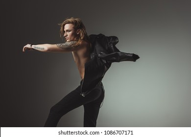 Tattooed Rocker Man With Long Hair In Black Leather Jacket, Isolated On Grey