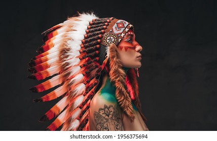Tattooed trendy woman wearing national headwear from feathers