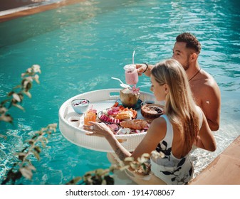 Tattooed Woman With Her Handsome Boyfriend Enjoys Tropical Food And Swim In A Pool In Thailand.