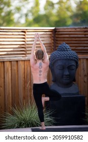 Tattooed woman in a standing Yoga pose.