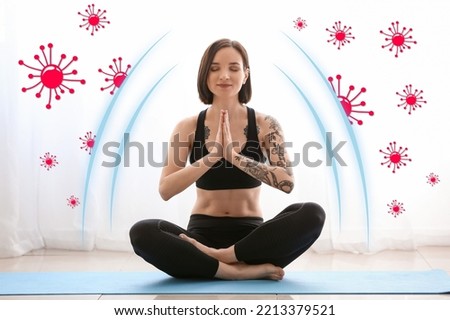 Tattooed young woman practicing yoga at home. Concept of strong immunity