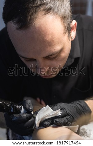 Tattooist makes a tattoo on the hand close up