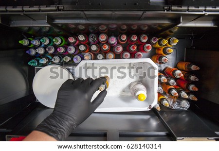 Tattooist selects a color from a box full of tattoo ink bottles. Overhead shot