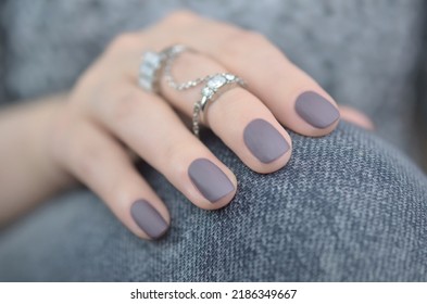 Taupe matte manicured nails in front of fabric.