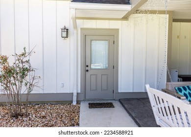 A taupe rear side back door of a new construction cream color house with hardy board siding near the patio entrance. - Powered by Shutterstock