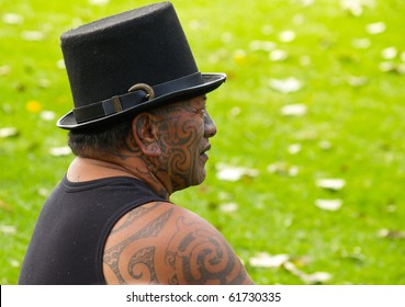 TAURANGA, NEW ZEALAND - APRIL 3: Maori Male Watching Musicians On Outdoor Stage On April 3, 2010 In Tauranga, New Zealand. Maori Activist Tama Iti Wears Hat And Traditional Moko Or Facial Tattoos.