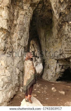 Tavda Caves ("Tavdinskiye Peshchery") in Altai, Russia. Spring scenic russian nature. Tourist girl in folk Pavlovo Posad shawl, scarf. Altay landscape, scenery. Natural beauty. Ancient cave, stones