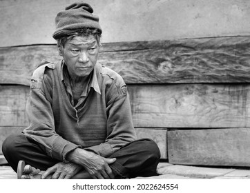 TAWANG, INDIA - SEPTEMBER 16, 2011: Portrait of older man from Sherdukpen ethnic tribe sitting outside house with sad expression  on September 16, 2011 near Tawang, Arunachal Pradesh, India.