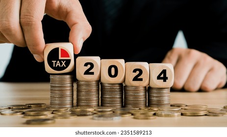 Tax 2024.Hand putting tax icon in the wooden cube for income tax return.Tax, investment, financial, savings and New Year Resolution concepts.
