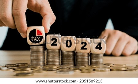 Tax 2024.Hand putting tax icon in the wooden cube for income tax return.Tax, investment, financial, savings and New Year Resolution concepts.