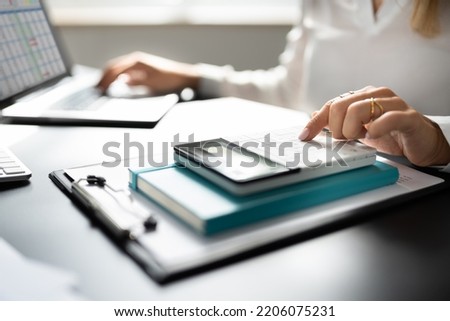 Tax Account Using Calculator. Business Ledger Record On Computer