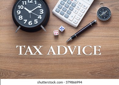 Tax Advice Words Written On Wooden Table With Clock,dice,calculator Pen And Compass