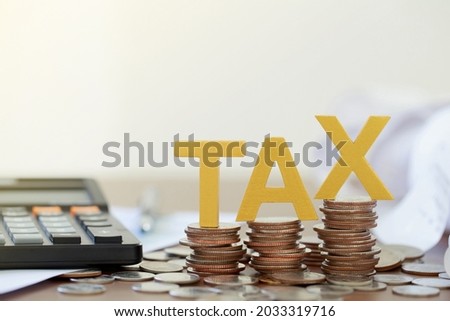 Tax Concept.Word tax put on coins and paper bill with coins on desks.