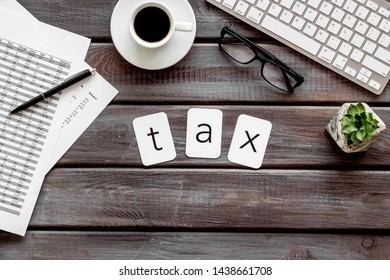 Tax copy on accountant work place with keyboard, coffee and glass on wooden desk background top view