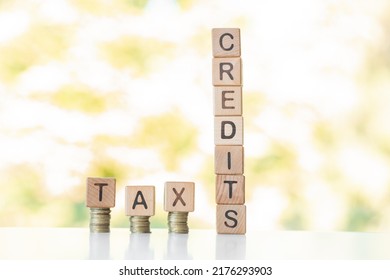 Tax Credits Word Written On Wood Cubes, Stacks Of Coins, Nature Green Background.