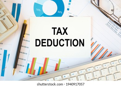 TAX DEDUCTION is written in a document on the office desk with office accessories, keyboard and diagram - Shutterstock ID 1940917057