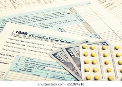 Tax Form 1040 with dollars and pills. Filtered image: cross processed vintage effect.