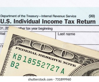 Tax form with one hundred dollar bill. close up.