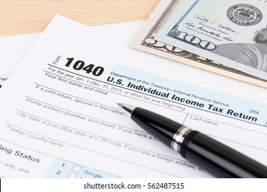 Tax form with pen, and dollar banknote - Shutterstock ID 562487515