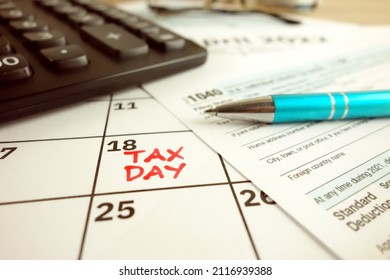 Tax payment day marked on a calendar - April 18, 2022 with 1040 form, financial concept - Shutterstock ID 2116939388