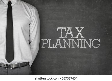 Tax Planning Text On Blackboard With Businessman Standing Side