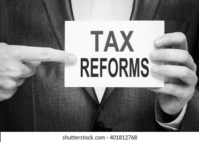 Tax Reforms. Man holding a card with a message text written on it.