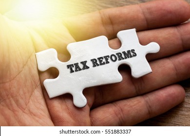 TAX REFORMS written on White color of jigsaw puzzle with hand,conceptual
